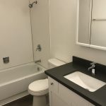 College Street Apartments bathroom with white cabinets and dark counters