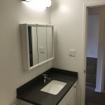 College Street Apartments bathroom with white cabinets and dark counters