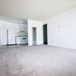 Sherwood & Forest Arms Apartments white kitchen cabinets and appliances with beige counters and multi-color tile floors view from living area