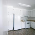 Sherwood & Forest Arms Apartments white kitchen cabinets and appliances with beige counters and multi-color tile floors