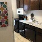 Alvarado Parkside kitchen area with dark cabinets and white counters